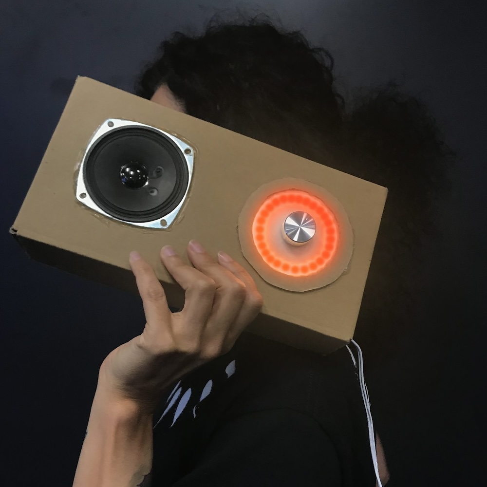 A person holding up a radio-like object made of cardboard and leds
