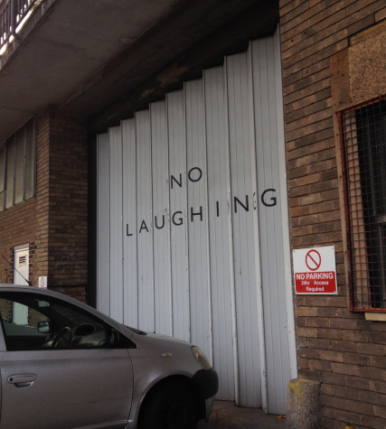 A vertically corrugated industrial door at Spike Island, saying 'no laughing' withone letter on each of the shutter panes